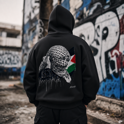 Hoodie Boxy zippé polaire homme avec l’œuvre Witness de Bandit, issue de sa série réalisée en Palestine. devant mur street art